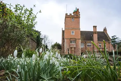 a building with a tower in the background with white flowers at Spacious Country House Apartment in Newmarket