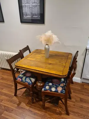 a wooden table with two chairs and a vase on it at Beautiful Country House Apartment in Newmarket
