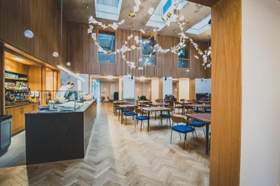 a restaurant with wooden floors and tables and chairs at Newnham College - University of Cambridge in Cambridge