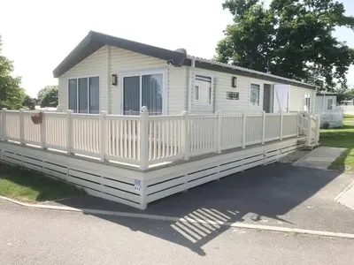 a white mobile home with a white fence at Mikanda Lodge in Clacton-on-Sea