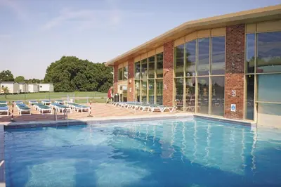 a large swimming pool with chairs and a building at Mikanda Lodge in Clacton-on-Sea