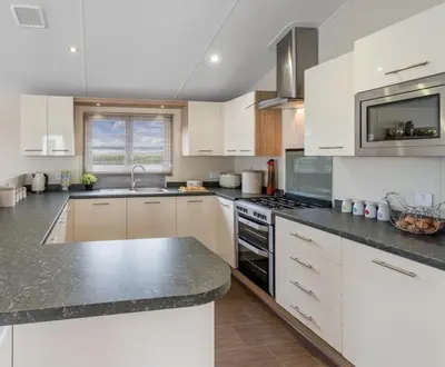 a kitchen with white cabinets and a black counter top at Mikanda Lodge in Clacton-on-Sea