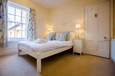 a bedroom with a white bed and a window at 14 Market Cross Place - Beachfront location with lovely sea views - Aldeburgh Coastal Cottages in Aldeburgh