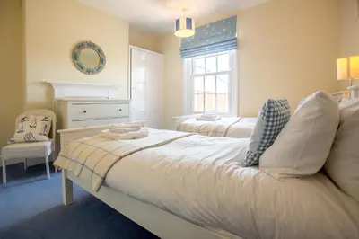 a bedroom with a bed and a chair and a window at 14 Market Cross Place - Beachfront location with lovely sea views - Aldeburgh Coastal Cottages in Aldeburgh