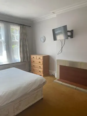 a bedroom with a bed and a tv on the wall at Brookside Lodge in Baldock