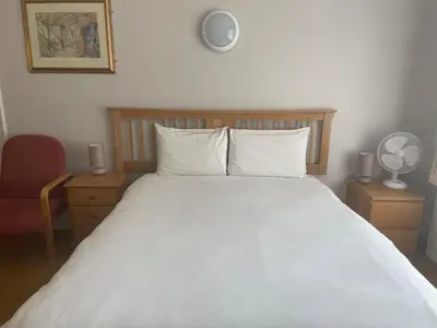 a bedroom with a large bed with white sheets and pillows at Brookside Lodge in Baldock