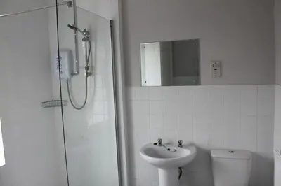 a bathroom with a shower and a sink and a toilet at Brookside Lodge in Baldock