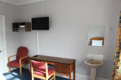 a bathroom with a desk and a sink and a chair at Brookside Lodge in Baldock