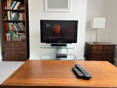a remote control sitting on a table with a television at 200m To Botanical Garden 3 Bedroom Victoria House in Cambridge