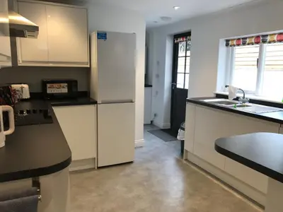a kitchen with white cabinets and a black counter top at 200m To Botanical Garden 3 Bedroom Victoria House in Cambridge