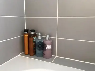 a shelf in a bathroom with bottles of liquid at 200m To Botanical Garden 3 Bedroom Victoria House in Cambridge