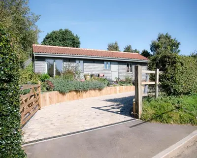 a house with a fence and a driveway at Hill Stables, Ufford in Ufford