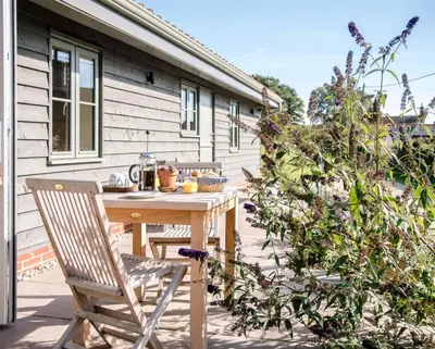 a wooden table and chairs on a patio at Hill Stables, Ufford in Ufford