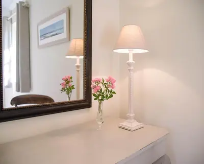 a vase of flowers on a table in front of a mirror at Hill Stables, Ufford in Ufford