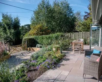 a garden with a patio with chairs and flowers at Hill Stables, Ufford in Ufford