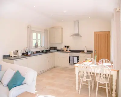 a kitchen and living room with a table and chairs at Hill Stables, Ufford in Ufford