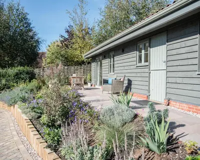a garden in front of a house with plants at Hill Stables, Ufford in Ufford