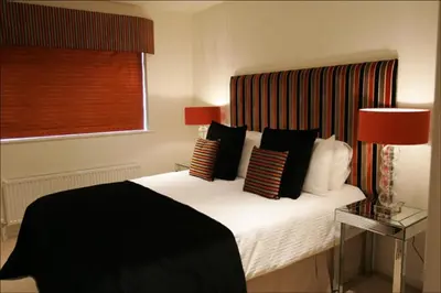 a bedroom with a bed with black and white pillows at Chelmsford Serviced Apartments in Chelmsford
