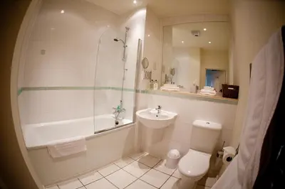 a bathroom with a tub and a toilet and a sink at Chelmsford Serviced Apartments in Chelmsford