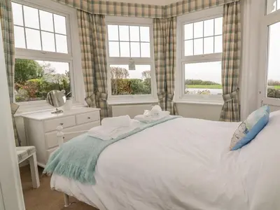 a bedroom with a large white bed with windows at Flat 1, Cambridge Court in Frinton-on-Sea