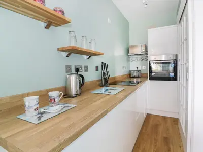 a kitchen with white counters and a wooden counter top at Flat 1, Cambridge Court in Frinton-on-Sea