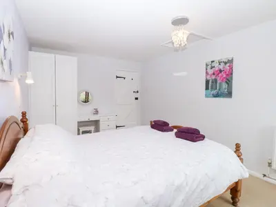 a white bedroom with a large white bed with purple pillows at Lowbrook Cottage in Diss