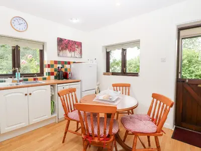 a kitchen with a table and chairs and a sink at Lowbrook Cottage in Diss