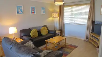 a living room with a couch and a television at Poplars in Aldeburgh