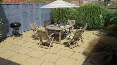 a table and chairs with an umbrella and a grill at Poplars in Aldeburgh