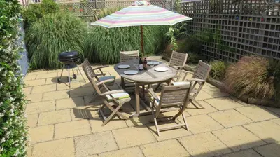 a table and chairs with an umbrella and a grill at Poplars in Aldeburgh