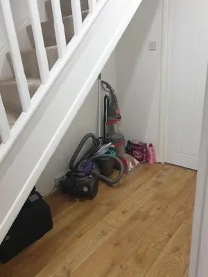 a room with a vacuum cleaner sitting under a staircase at Fully equipped Large 3 bedroom in Bishops Stortford