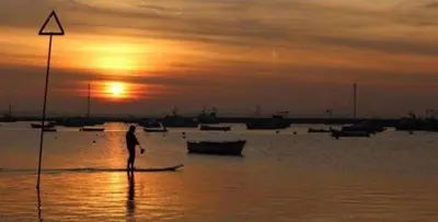a man standing on a boat in the water at sunset at The Mariners Suite in West Mersea