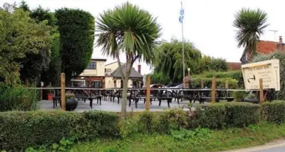 a group of tables and palm trees in a park at The Mariners Suite in West Mersea