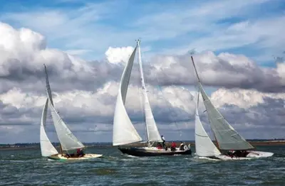 three sailboats in the water under a cloudy sky at The Blackwater Suite in West Mersea