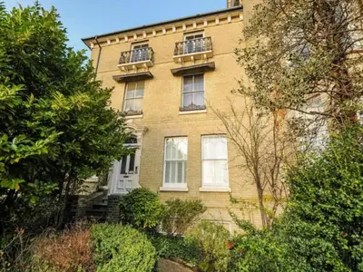 a yellow brick building with two windows and bushes at Toothbrush Apartments - Central Ipswich - Fonnereau Road in Ipswich