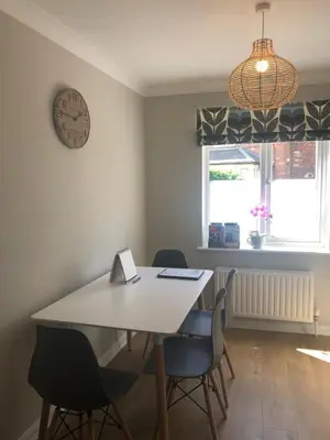 a dining room table with chairs and a clock on the wall at 1 WATER PUMP HOUSE in Bury Saint Edmunds