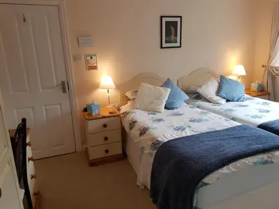 a bedroom with two beds and a night stand with two lamps at The Brambles B&B in Waterbeach