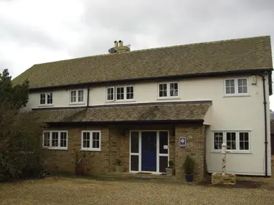 a white and brick house with a blue door at The Brambles B&B in Waterbeach