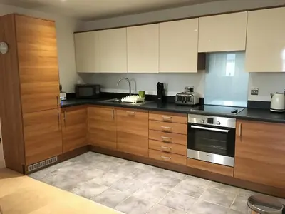 a kitchen with wooden cabinets and a stove at Toothbrush Apartments - Ipswich Waterfront - The Cambria in Ipswich