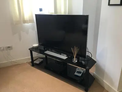 a large flat screen tv on a black stand at Toothbrush Apartments - Ipswich Waterfront - The Cambria in Ipswich