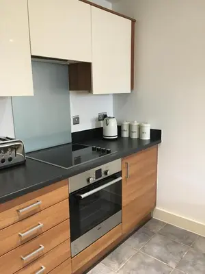 a kitchen with wooden cabinets and a stove top oven at Toothbrush Apartments - Ipswich Waterfront - The Cambria in Ipswich