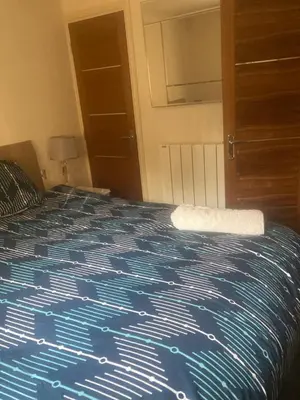 a bedroom with a bed with a blue comforter at 2 bedrooms Bell Cottage in Hoddesdon