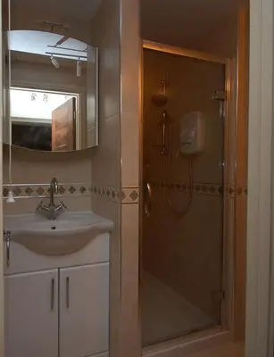 a bathroom with a shower and a sink and a mirror at 2 bedrooms Bell Cottage in Hoddesdon