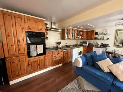 a kitchen with wooden cabinets and a blue couch at 2 bedrooms Bell Cottage in Hoddesdon