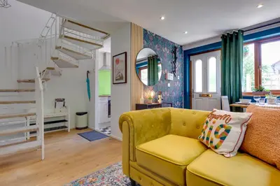 a living room with a yellow couch and stairs at Fully refurbished 1 bedroom in Cambridge