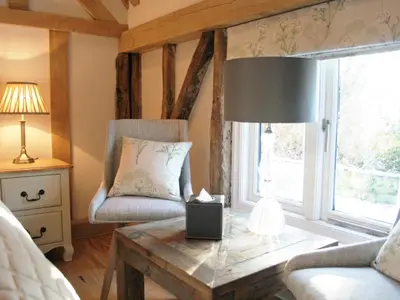 a living room with a table and a chair and a window at The Red Cow in Heydon