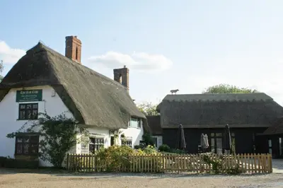 an old white building with a thatched roof at The Red Cow in Heydon