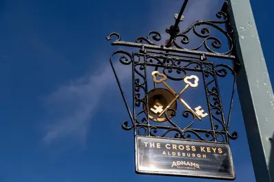 a sign on the side of a building with a clock at The Cross Keys, Aldeburgh in Aldeburgh