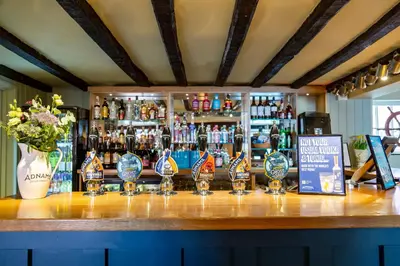 a bar with several wine glasses on a counter at The Cross Keys, Aldeburgh in Aldeburgh