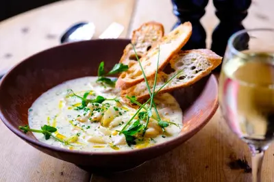 a bowl of soup with toast and a glass of wine at The Cross Keys, Aldeburgh in Aldeburgh
